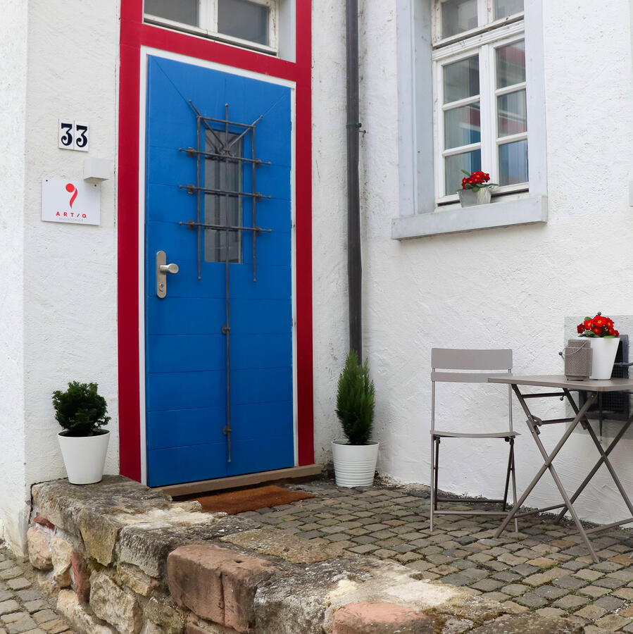 Eingang der ARTIQ Musikschule Mainz-Finthen Blaue Eingangstür der ARTIQ Musikschule in der Poststraße 33 in Mainz-Finthen mit Sitzgelegenheit vor dem Gebäude.