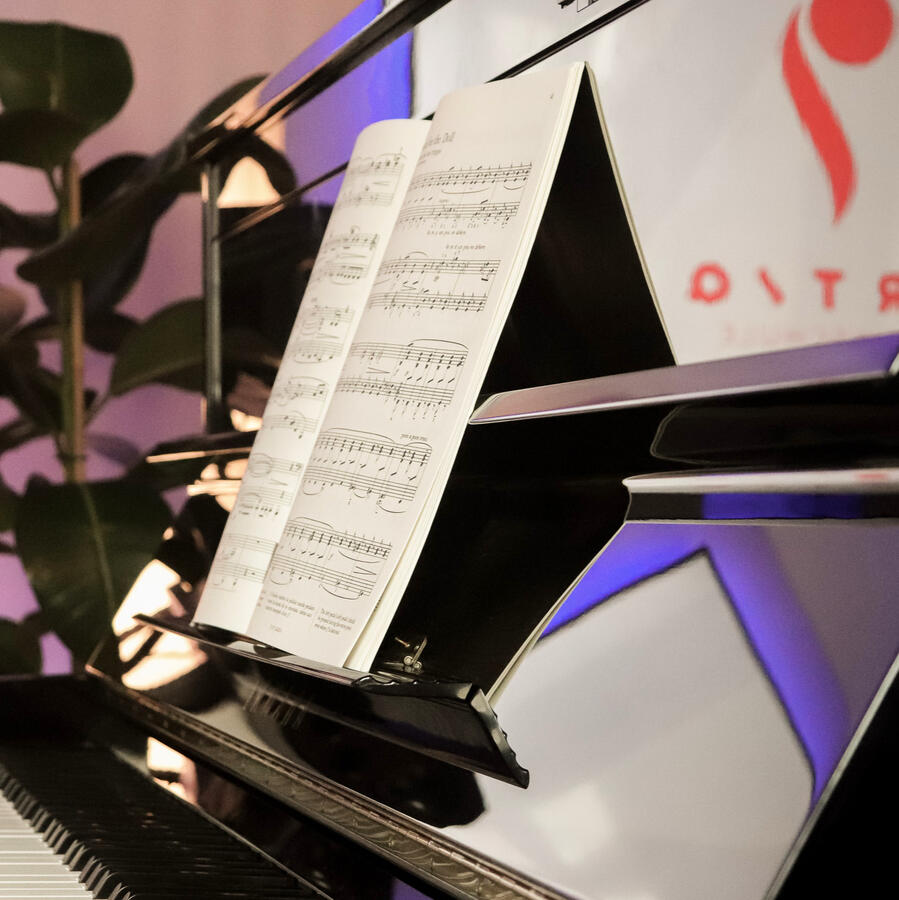 Klaviernoten im Detail – ARTIQ Musikschule Nahaufnahme eines Notenblattes auf dem glänzenden Klavier im Studio der ARTIQ Musikschule.