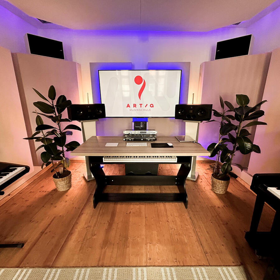 Tonstudio der ARTIQ Musikschule – Musikproduktion in Mainz Moderner Unterrichts- und Produktionsraum der ARTIQ Musikschule mit Schreibtisch, Lautsprechern und ARTIQ Logo auf dem Bildschirm.